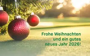 drei Weihnachtskugeln hängen an einem Tannenzweig auf einen Golfplatz