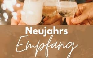 Anstoßende Sektgläser vor warmem Lichterhintergrund, darüber die Aufschrift ‚Neujahrsempfang